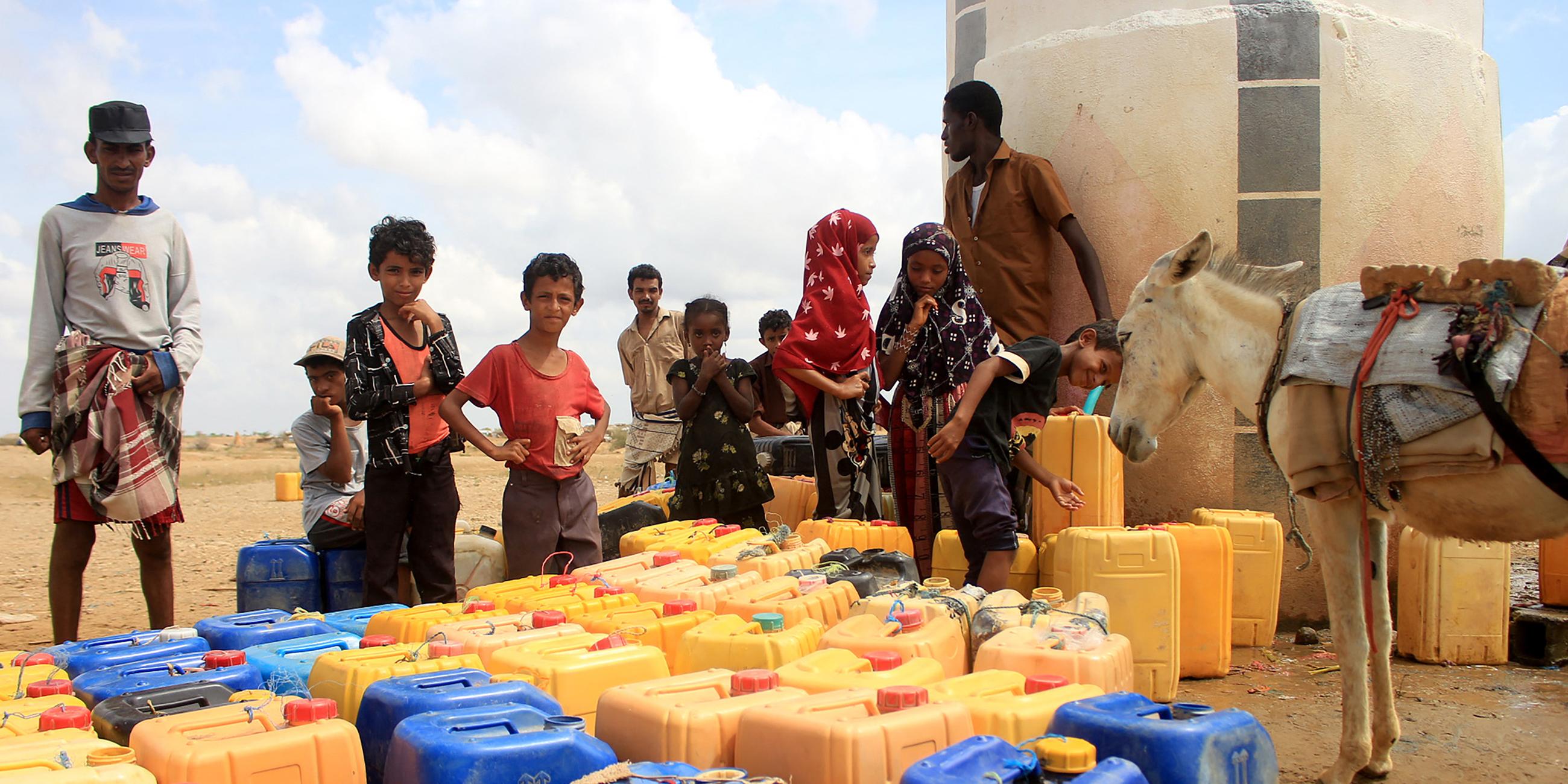 Jemenitische Kinder vor Wasserkanistern an einem Verteilungspunkt.