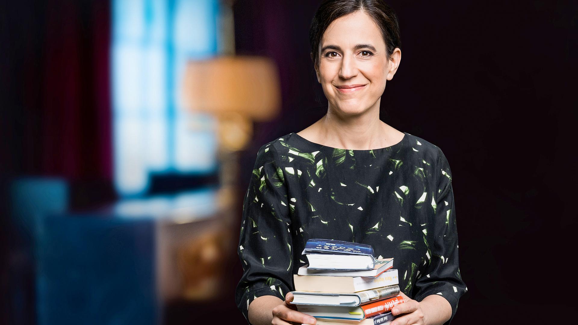 Lächelnde dunkelhaarige Frau mit Bücherstapel