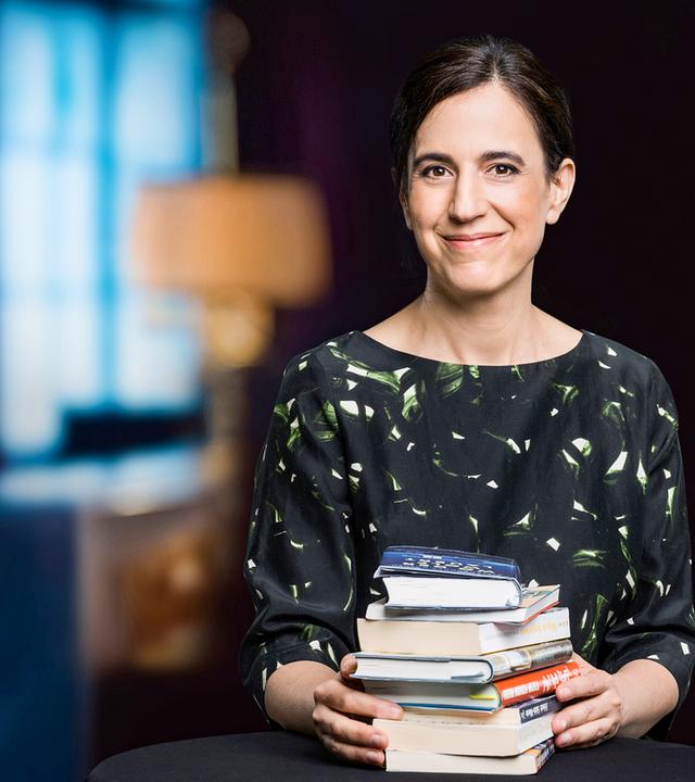 Lächelnde dunkelhaarige Frau mit Bücherstapel