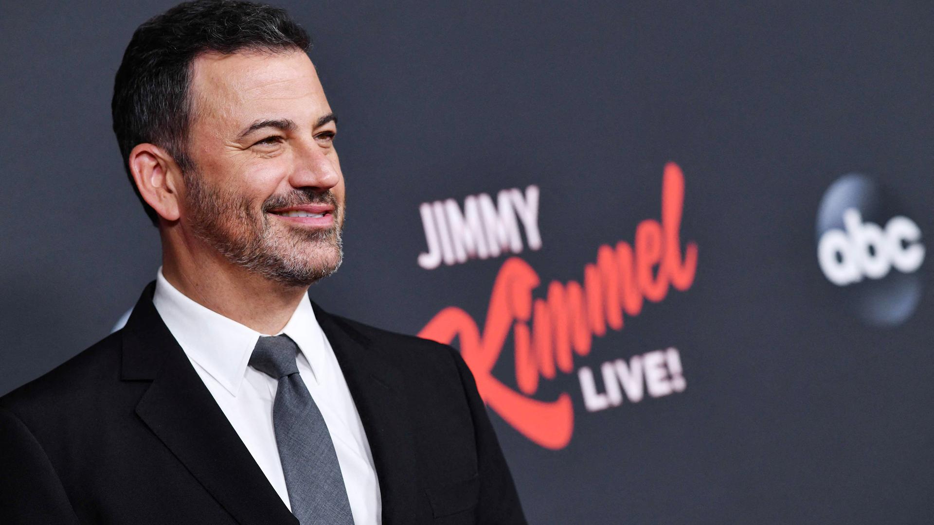 Ein Mann steht vor dunklem Hintergrund.