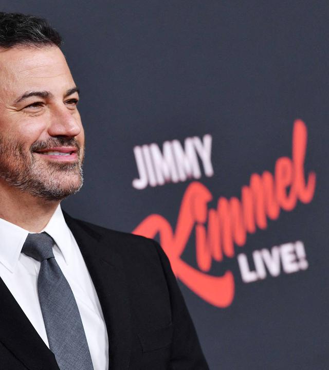 Ein Mann steht vor dunklem Hintergrund.