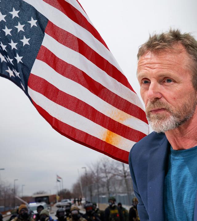 Ein Mann mittleren Alters mit graumeliertem Bart und kurzen Haaren ist vor ein Foto von einer US-Flagge bei einer Demonstration in Minneapolis montiert.
