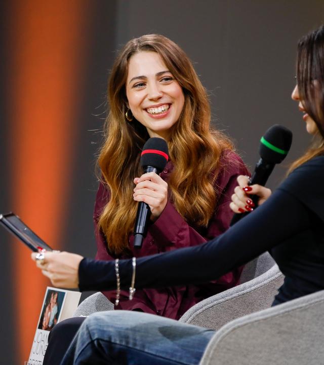Zwei junge Frauen sitzen nebeneinander und sprechen in Mikrofone.