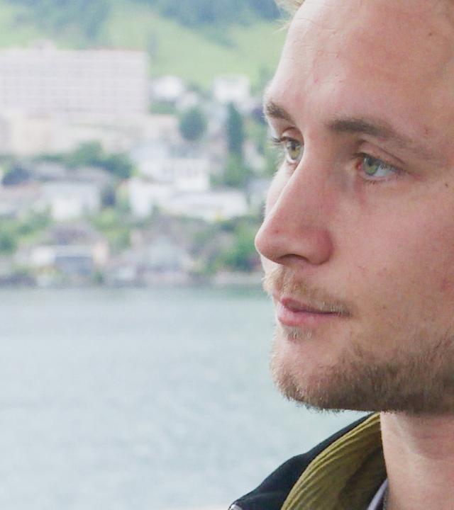 Ein Mann blickt nachdenklich, während er sich auf eine Tätigkeit konzentriert. Er ist von Barrieren in der Kommunikation durch Stottern betroffen.