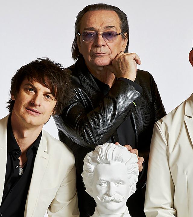 Drei Männer sthen um eine weisse Büste von Johann Strauss