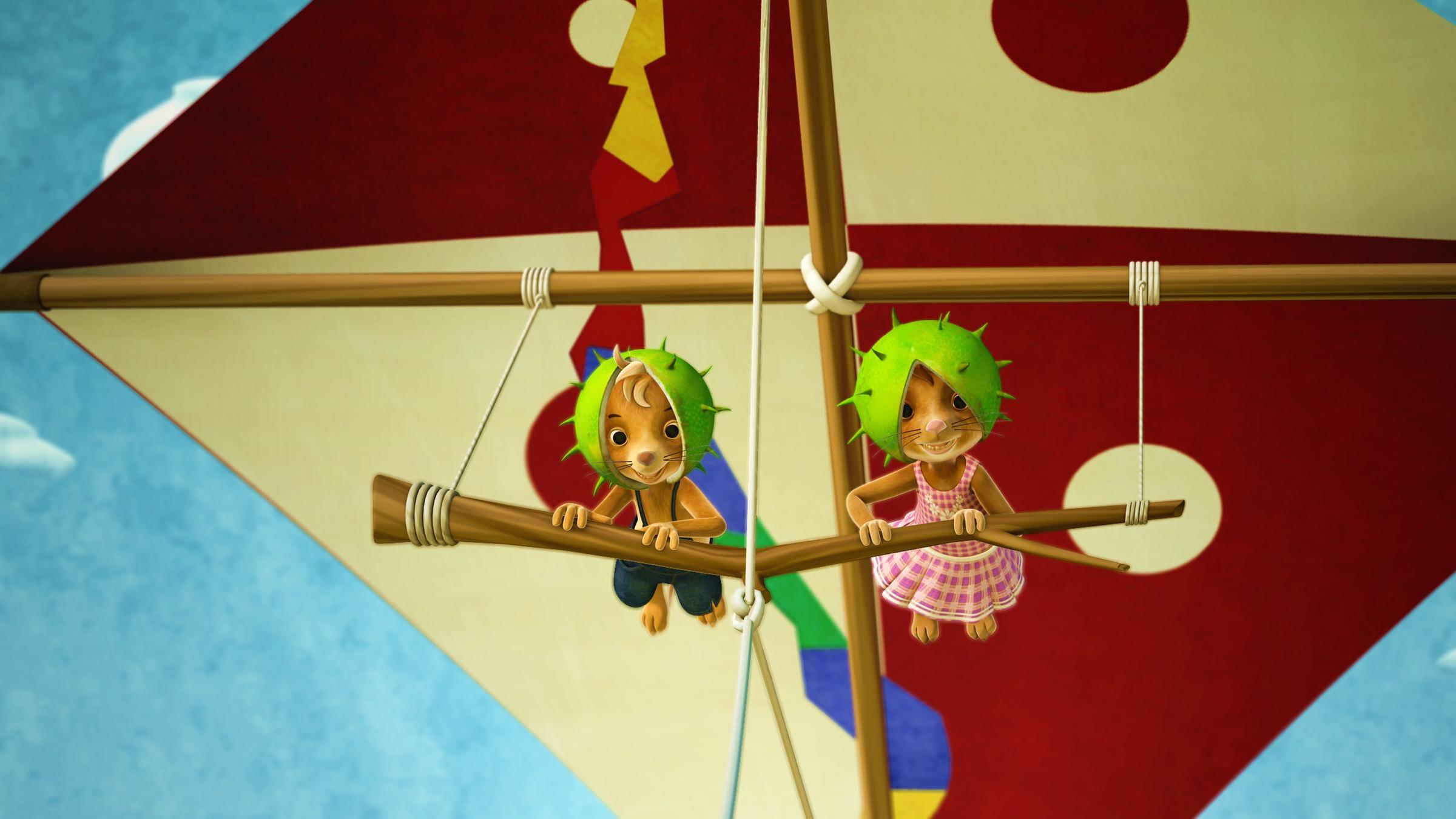 Jo und Naya fliegen mit dem neuen Drachenflieger in der Luft und haben grüne Kastanienschalen als Helme auf.