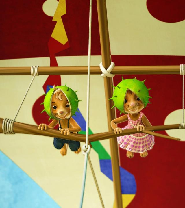 Jo und Naya fliegen mit dem neuen Drachenflieger in der Luft und haben grüne Kastanienschalen als Helme auf.