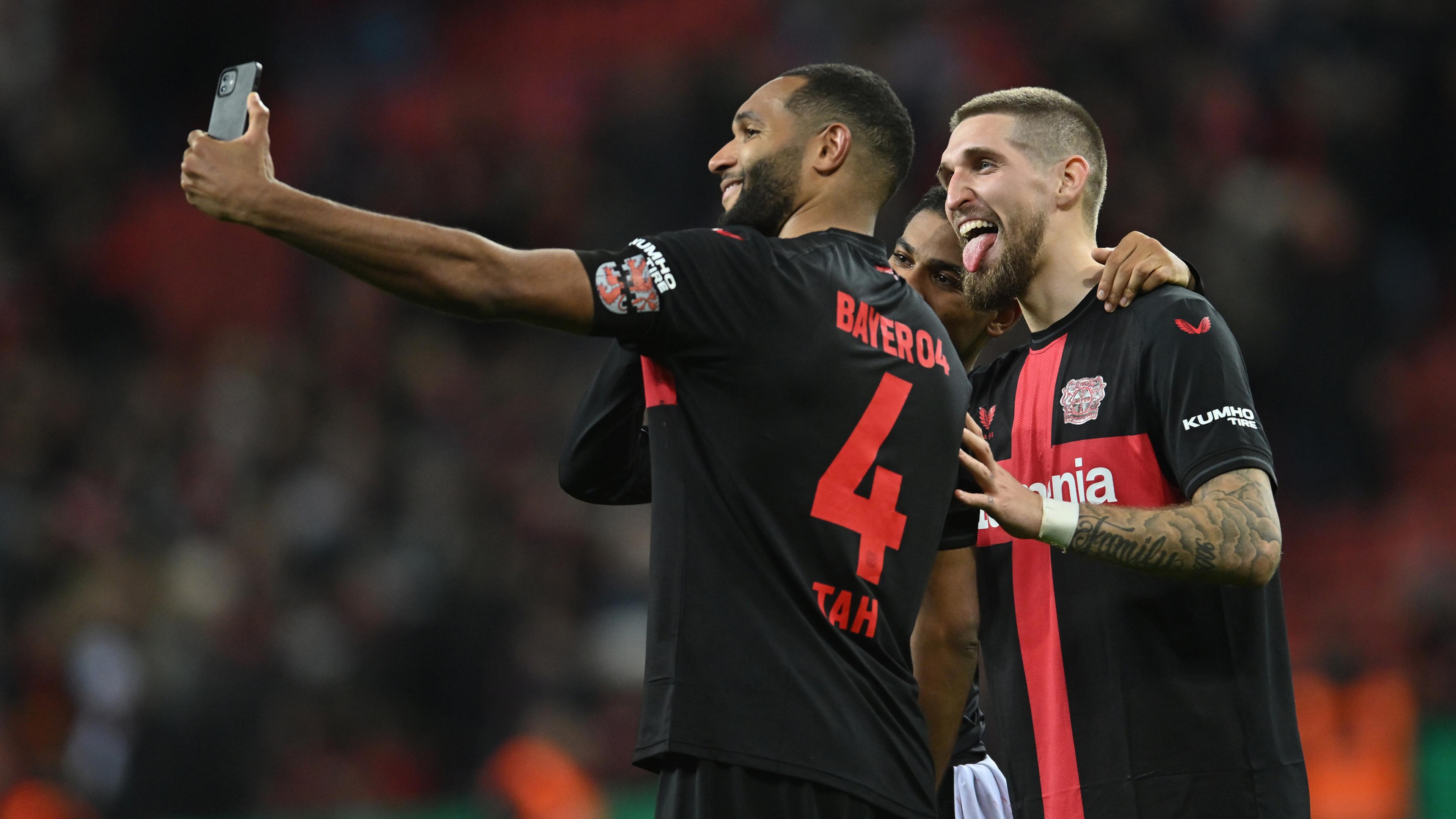 Jonathan Tah, Amine Adli et Robert Andrich (lr) de Leverkusen prennent un selfie après le match. 