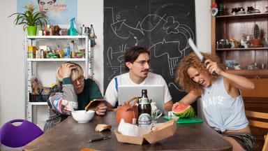 "Just Push Abuba": Joon (Joon Kim, l.), Toni (Anton Weil) und Lucia (Elli Tringou) sitzen am WG-Tisch. 