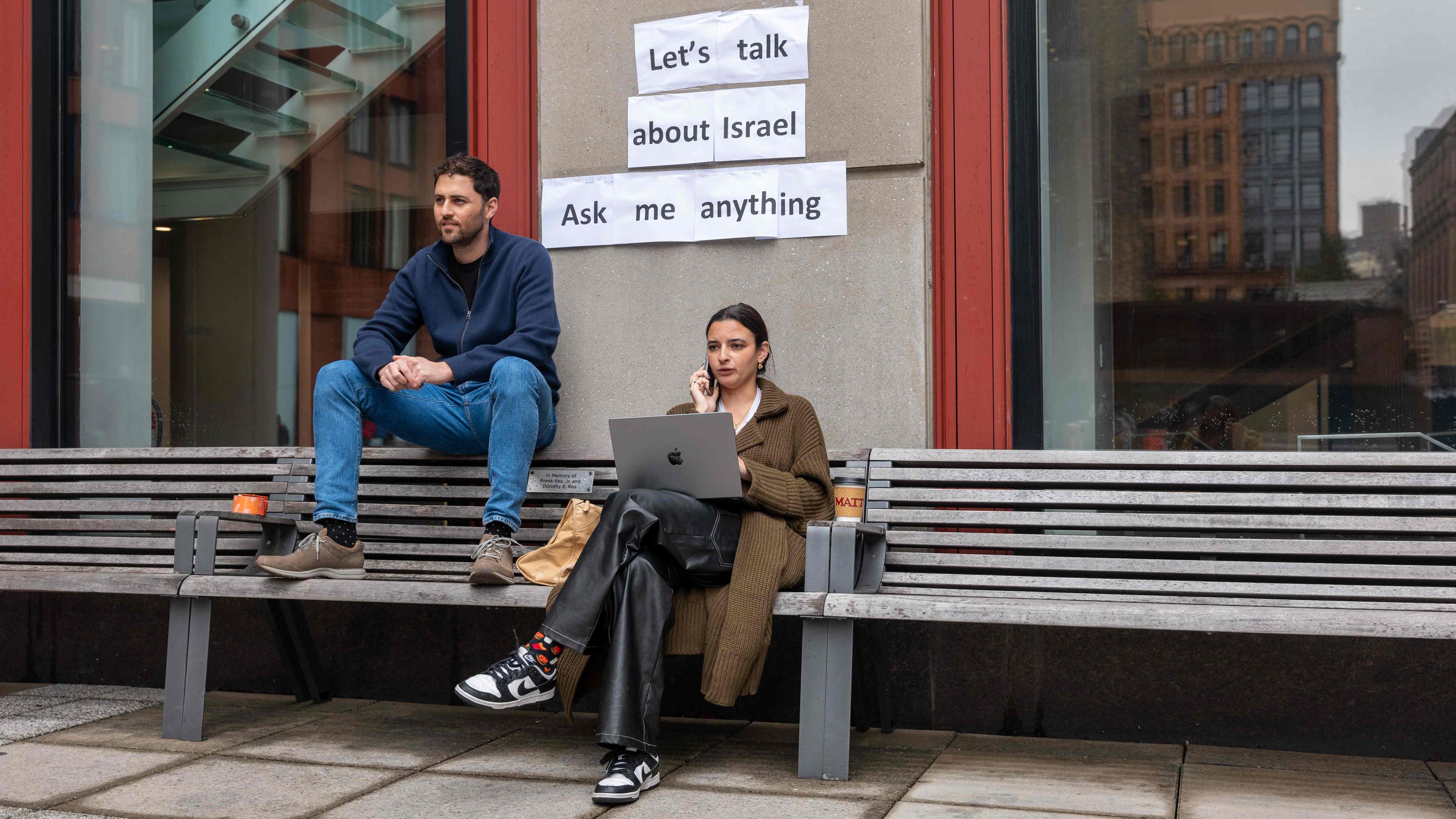 MAnn und Frau auf Bank, darüber Schild "Let's talk about Israel"