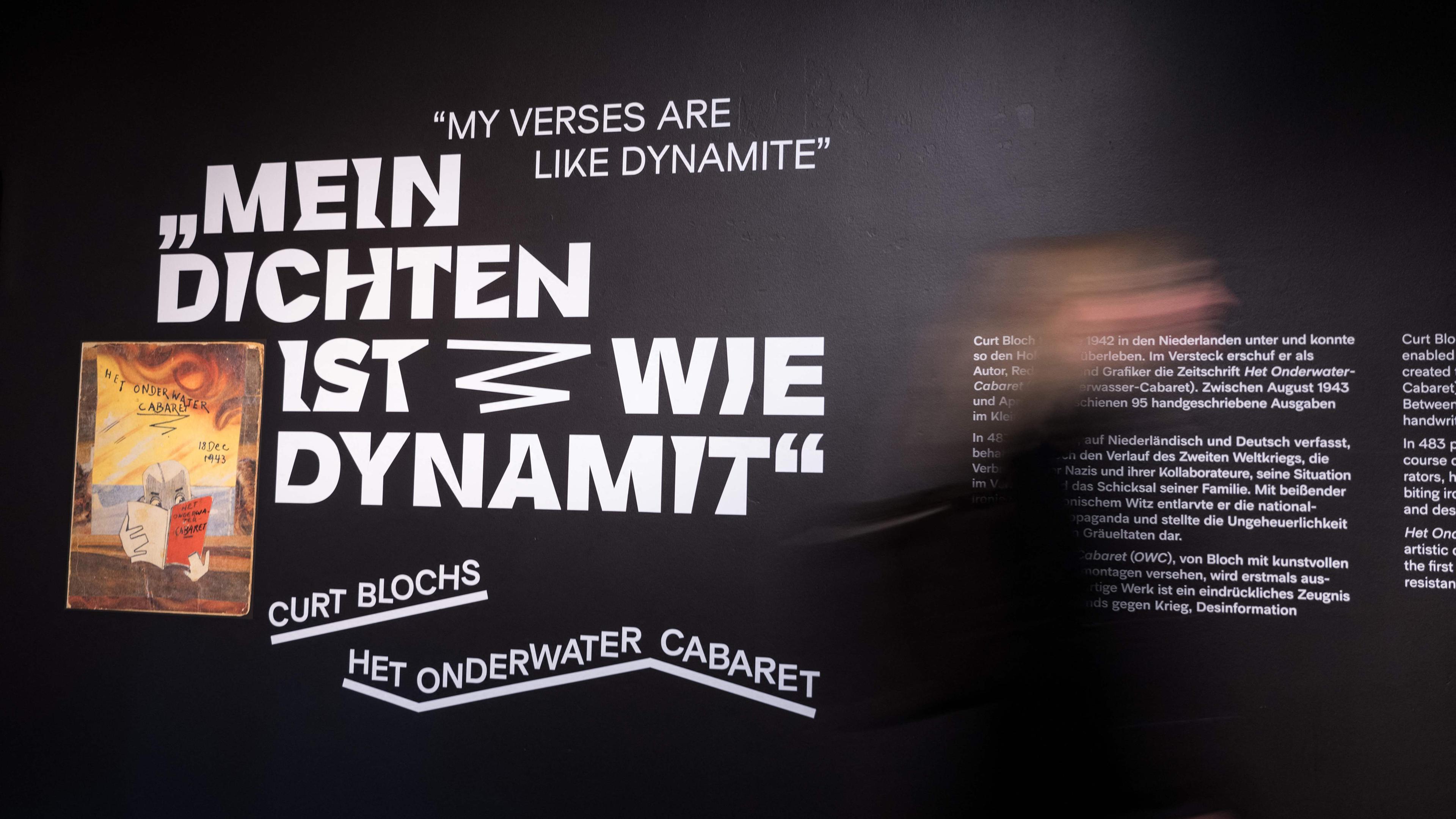 Besucher gehen an einer Wand mit dem Schriftzug "Meine Schrift ist wie Dynamit" vorbei.