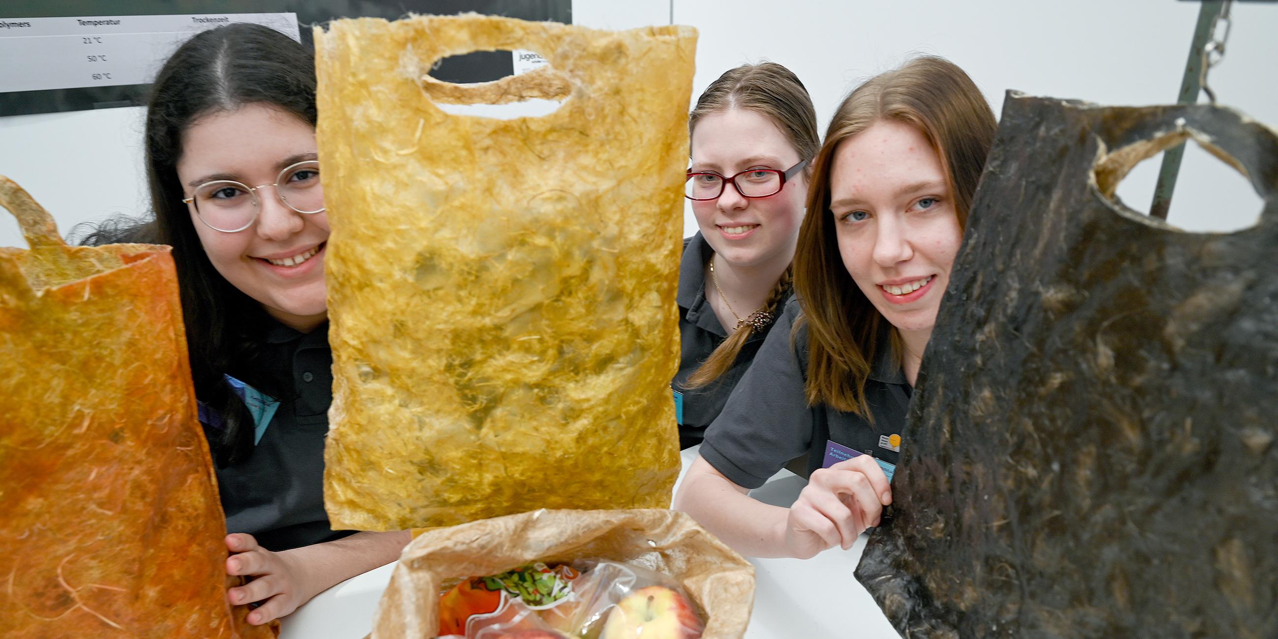 Seyma Celik (l-r), Anja Armstrong und Jennifer Boronowska mit ihrer kompostierbaren Einwegtüte