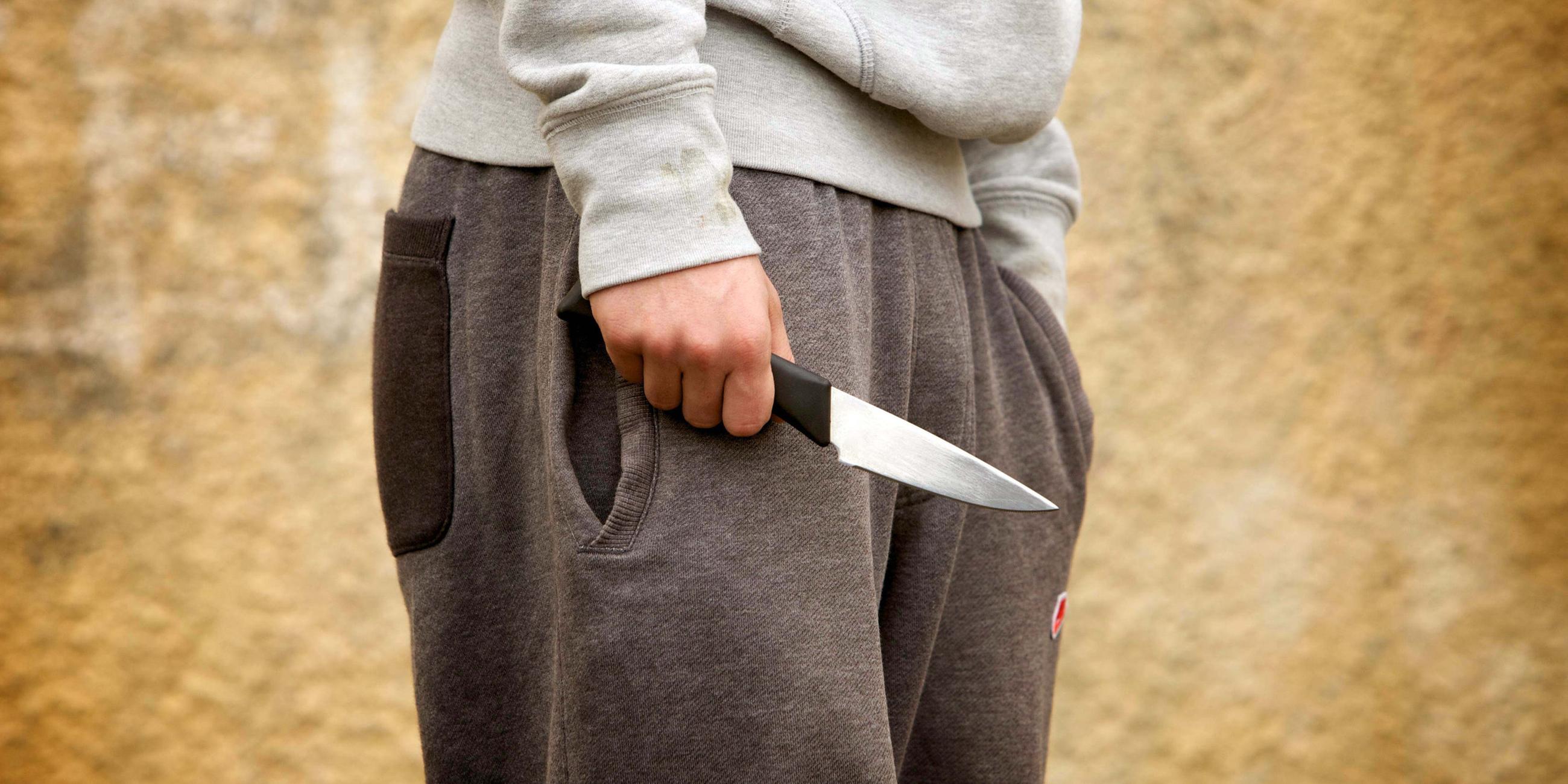 Zu sehen ist ein Symboldbild, in dem ein Junge ein Messer hält.