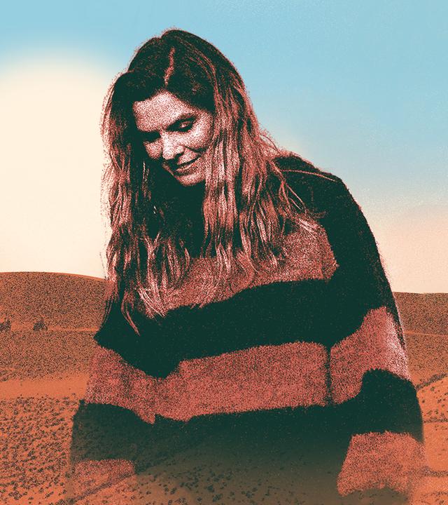 Ein Porträt von Eva Briegel von Juli vor der Wüste. Sie blickt nach unten. Neben ihr ist ein Kamel zu sehen.