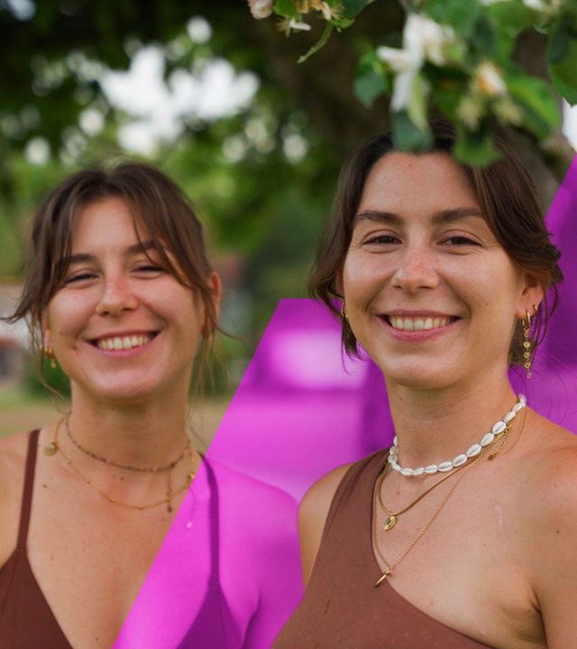 Julia und ihre Zwillingsschwester Eva stehen nebeneinander, Arm in Arm und lächeln in die Kamera. 