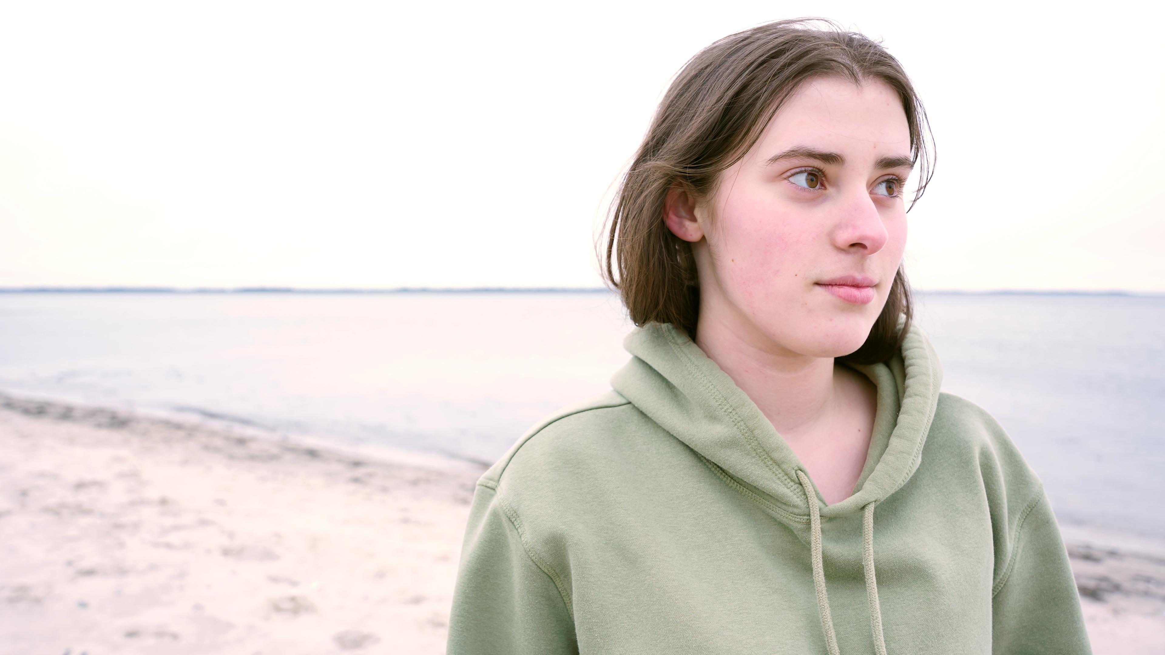 "Jung, begabt und seelisch krank - Wenn jugendliche Hilfe brauchen": Aliya steht am Strand, sie schaut in die Ferne auf das Meer.