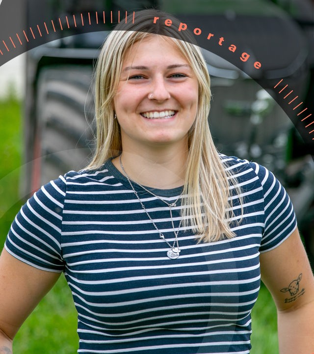 Lucy Schmidt steht lachend vor einem Traktor.