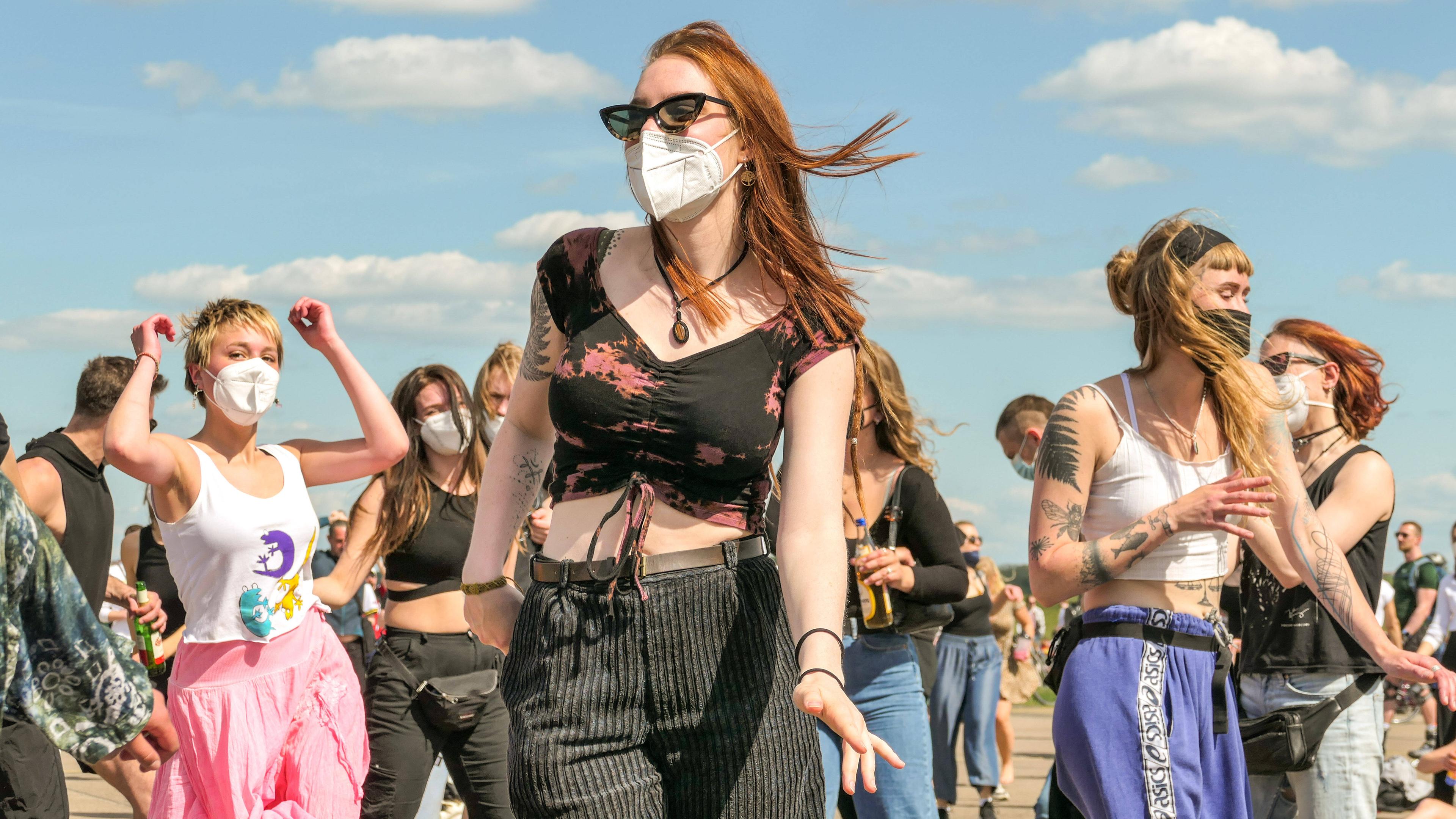 Junge Frauen tanzen mit Maske auf dem Tempelhofer Feld in Berlin