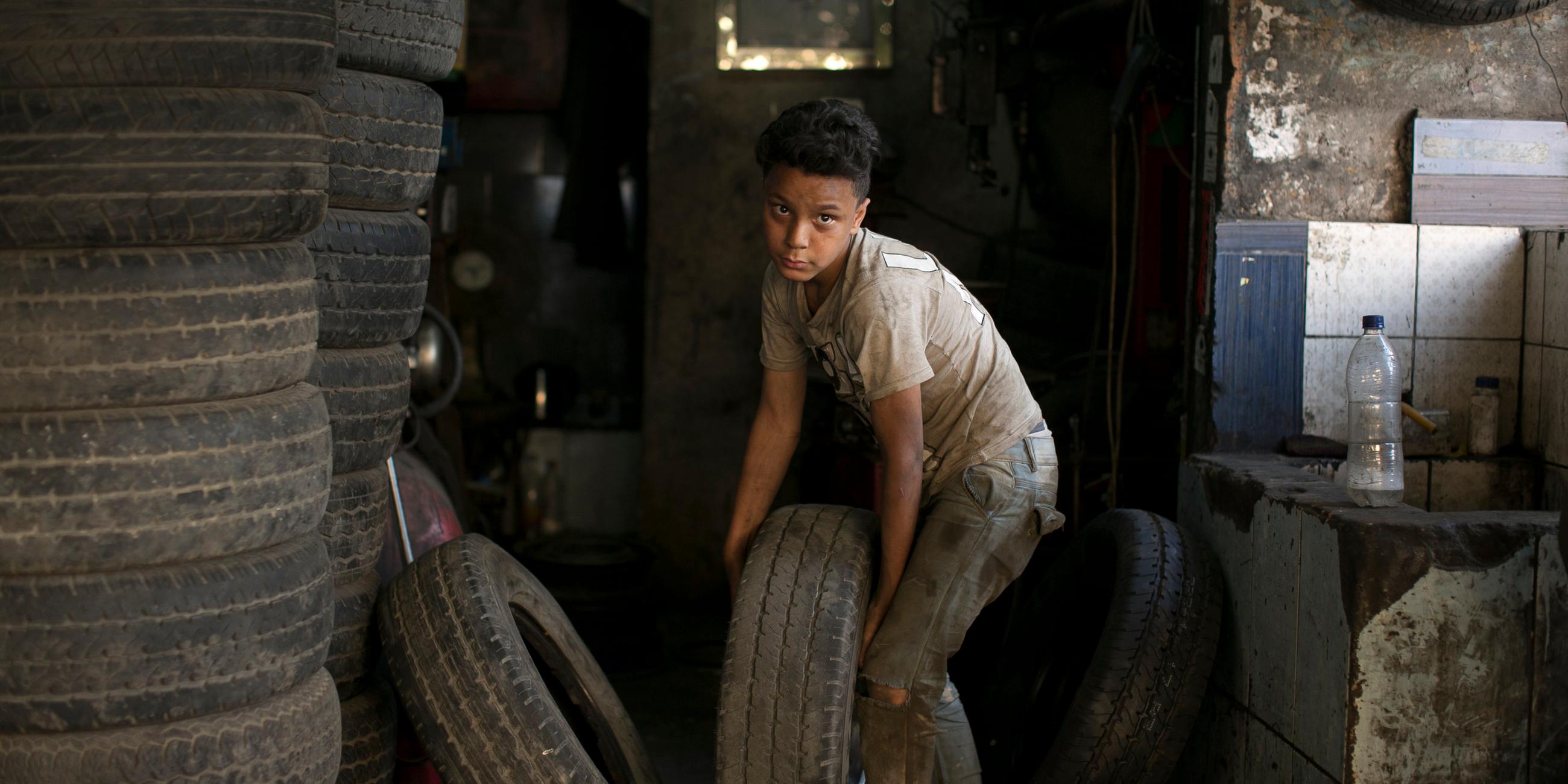 Junge trägt einen Reifen in eine Werkstatt in Kairo 