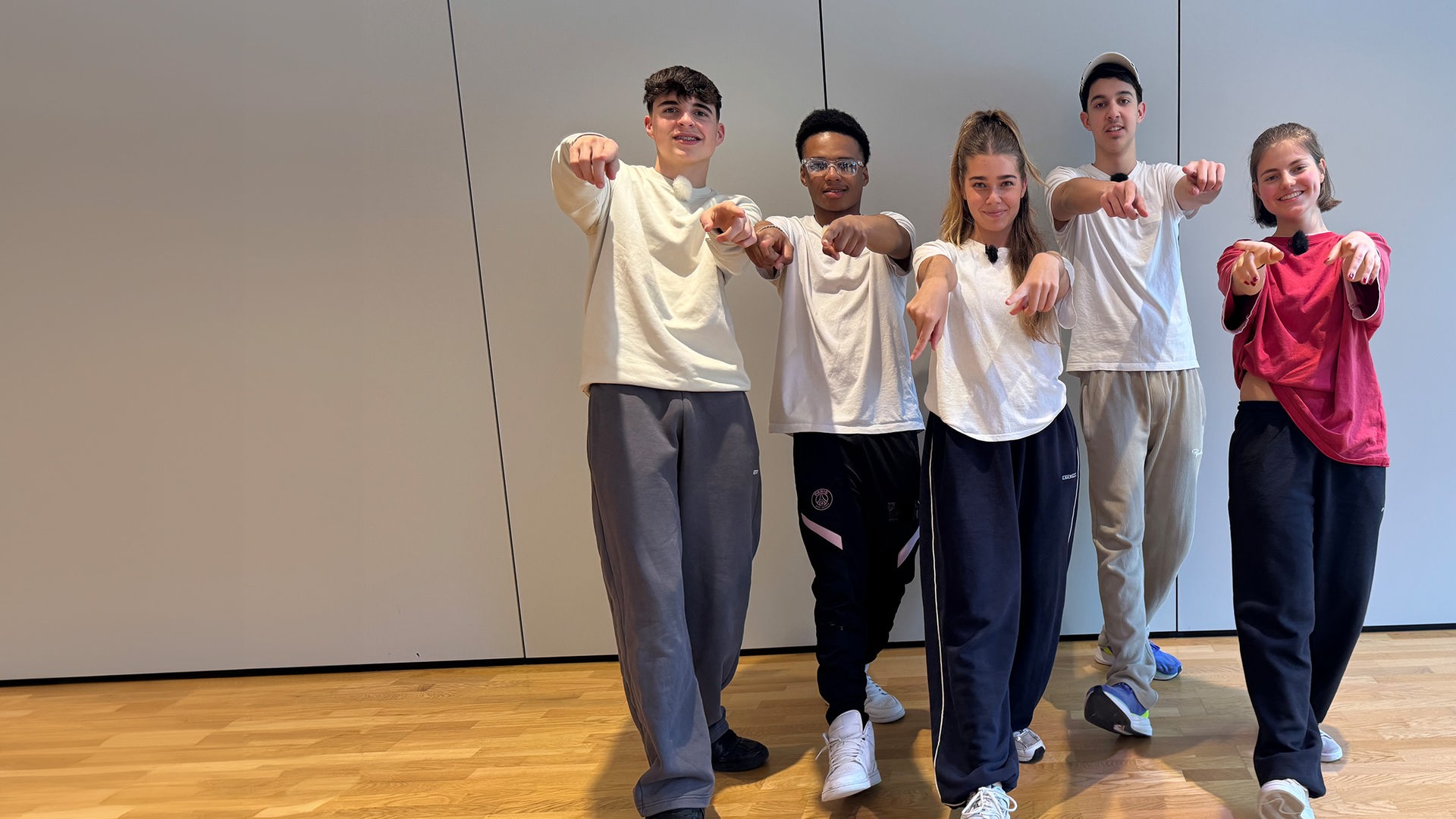 Auf dem Foto sind fünf Jugendliche mit Jogginghosen und T-Shirts zu sehen. Sie alle haben ein Bein nach vorne gestellt und zeigen mit beiden Händen auf den Fotografen. Es sind Nick, Azad und Lorian aus der Jungs-WG im Pitztal mit zwei Mädchen aus einem Tanzkurs.
