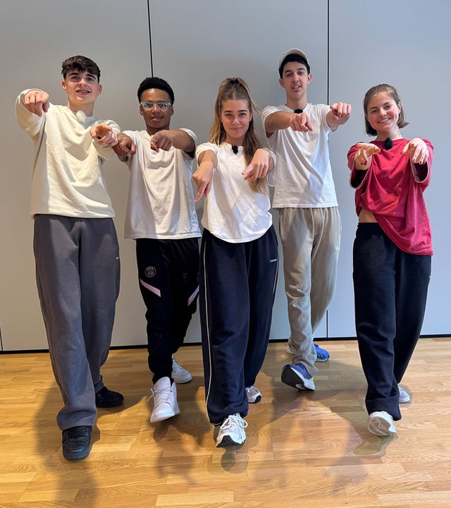 Auf dem Foto sind fünf Jugendliche mit Jogginghosen und T-Shirts zu sehen. Sie alle haben ein Bein nach vorne gestellt und zeigen mit beiden Händen auf den Fotografen. Es sind Nick, Azad und Lorian aus der Jungs-WG im Pitztal mit zwei Mädchen aus einem Tanzkurs.