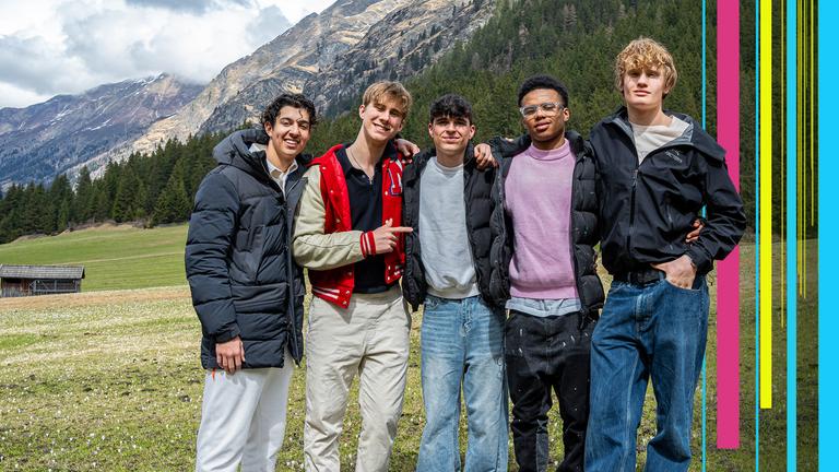 Lorian, Luke, Nick, Azad und Cay stehen auf einer Wiese - im Hintergrund die Berge