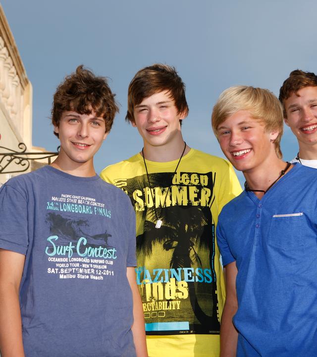 Die Jungs aus der Jungs-WG Mallorca stehen nebeneinander und lächeln in die Kamera