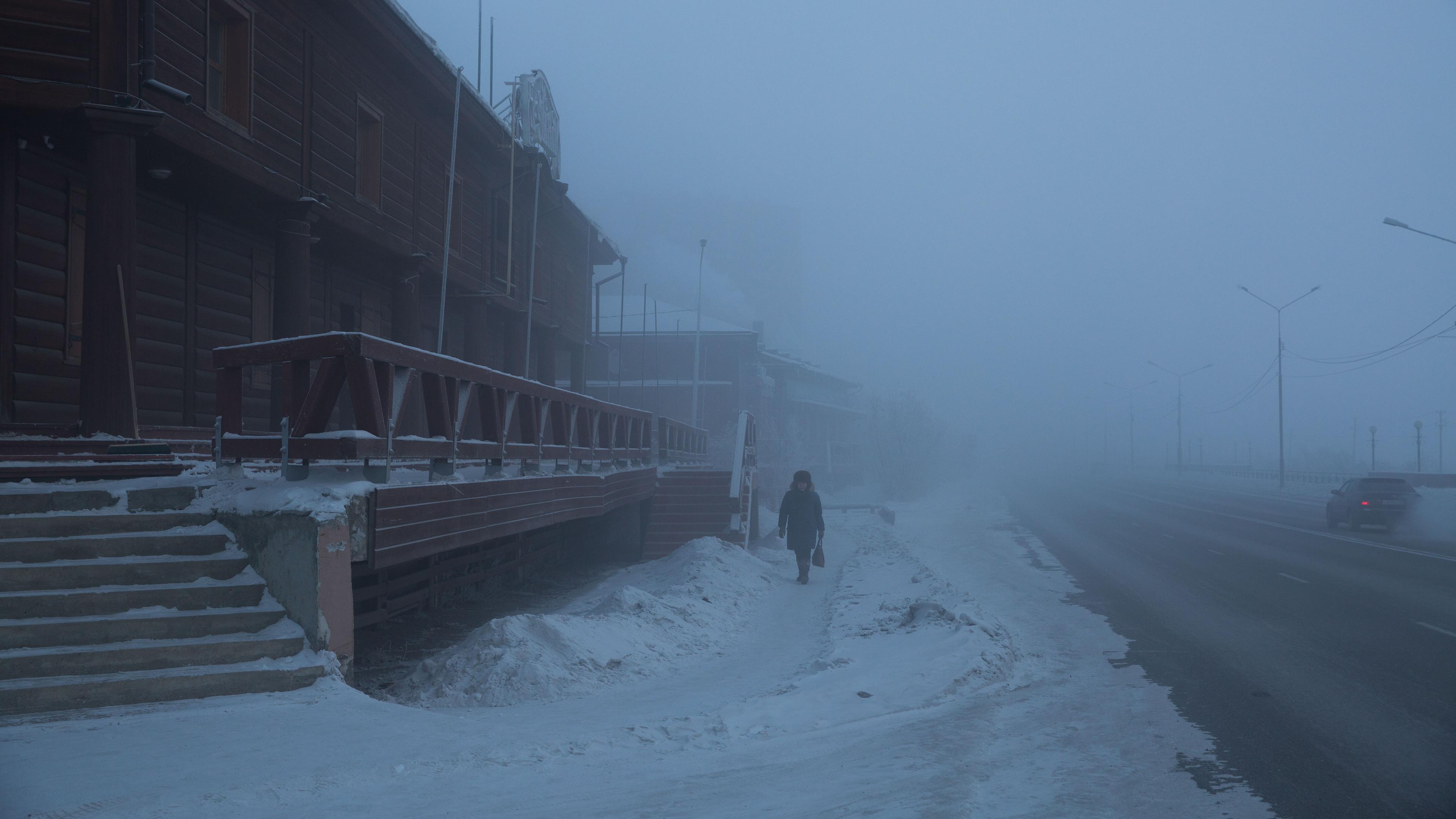 Russland, Jakutsk: Ein Anwohner läuft im dichten Schneetreiben durch eine alte Straße. Archivbild