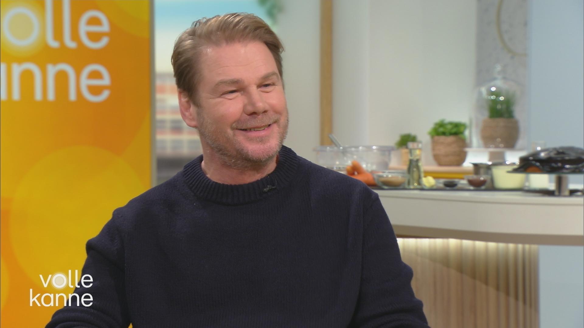 Schauspieler Kai Scheve sitzt im Volle-Kanne-Studio und lacht.