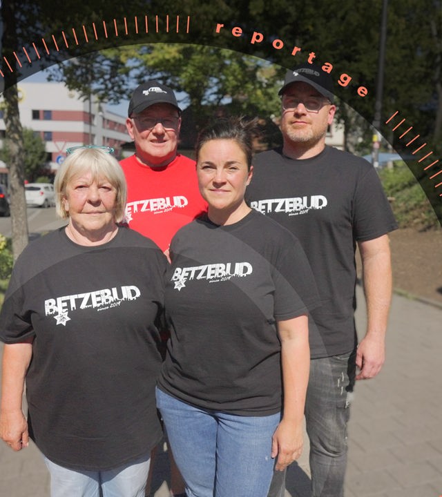 Helga Reitmayer, Armin Kraus, Sandy Kraus, Armin Kraus jr. stehen eng beieinander. Die zwei Männer tragen Mützen. Alle vier tragen T-Shirts mit der Aufschrift "Betzebud".