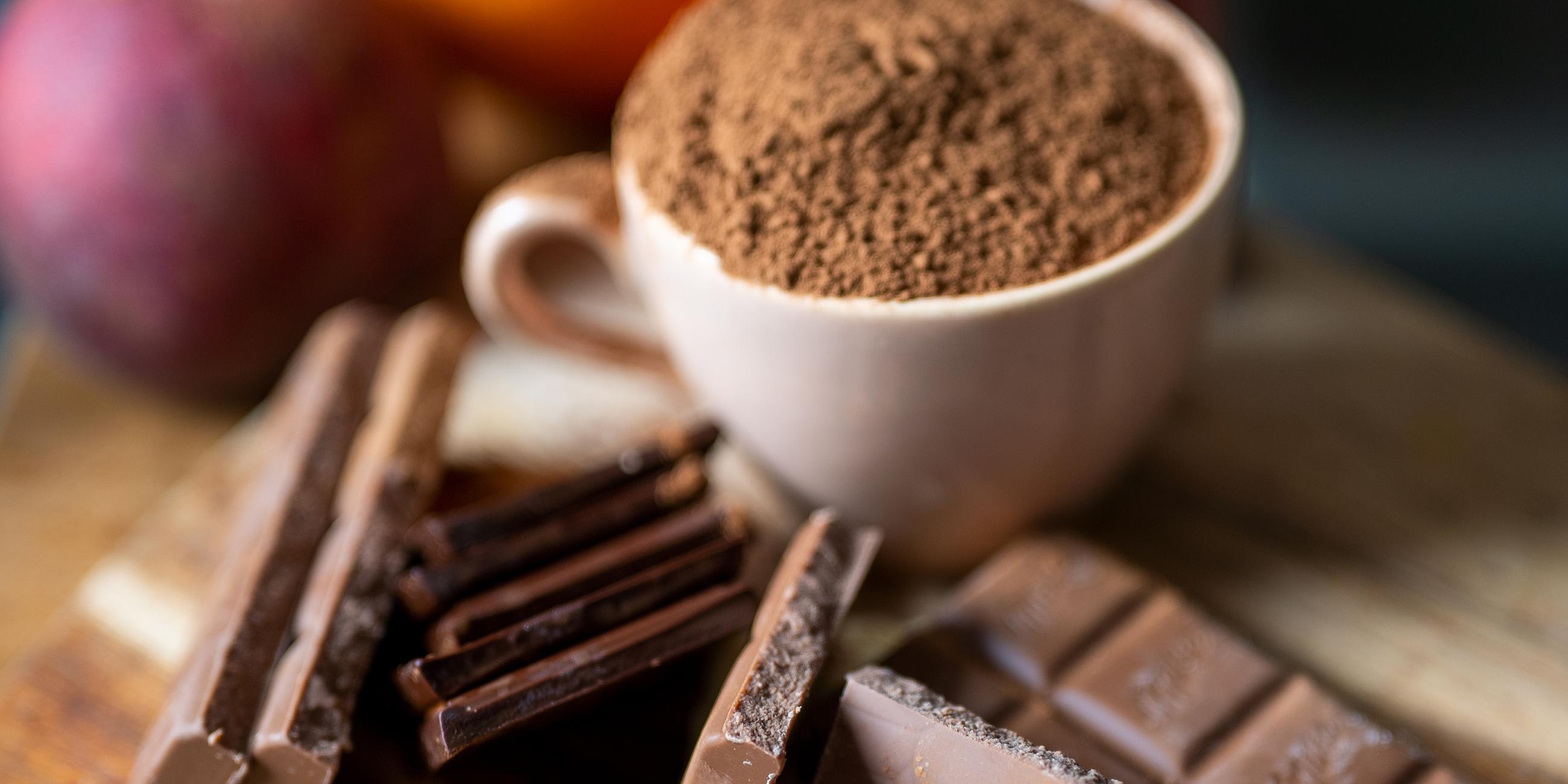 Schokolade neben einer mit Kakaopulver gefülltenTasse