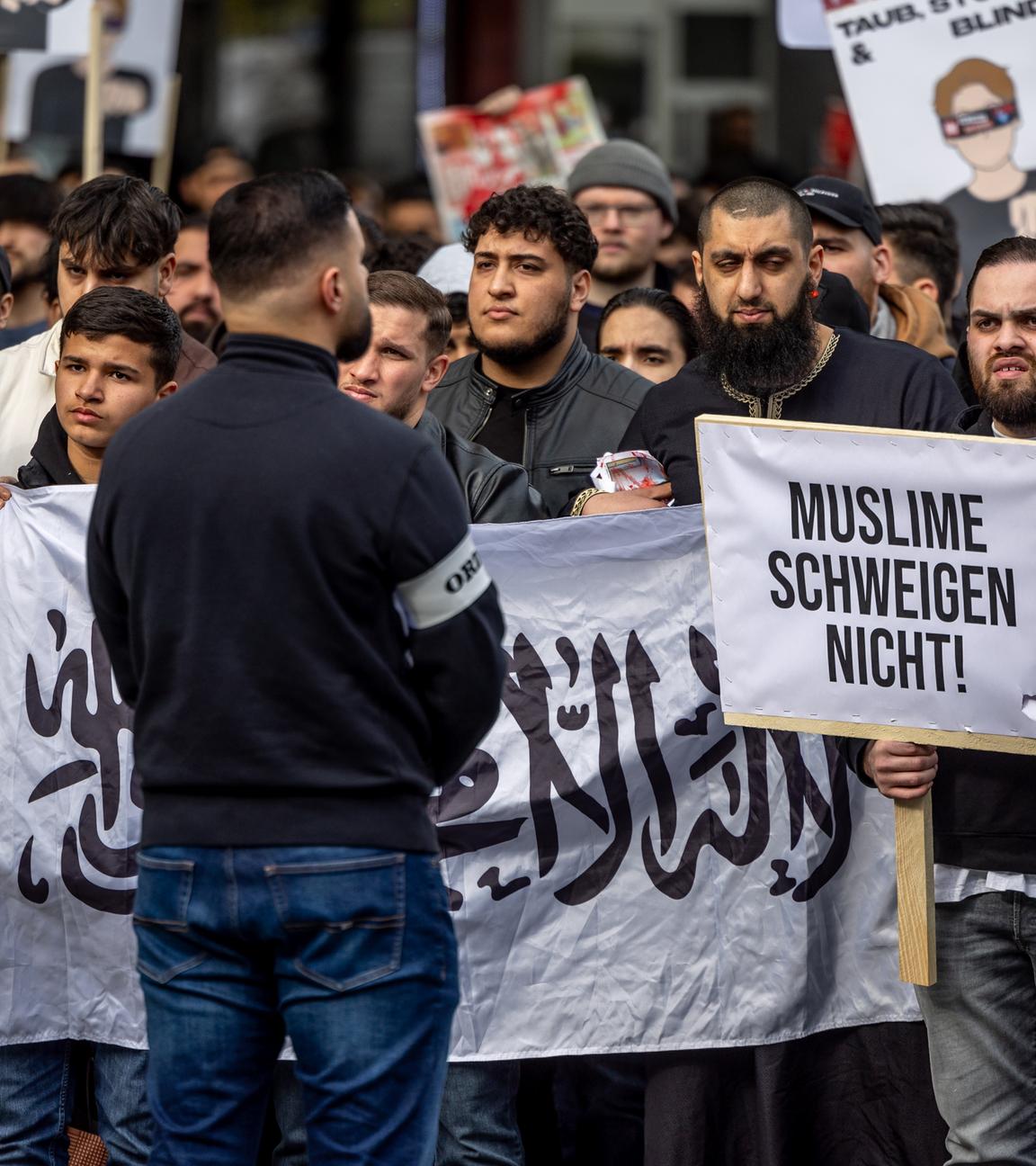 Hamburg: Teilnehmer einer Islamisten-Demo halten ein Plakat mit der Aufschrift ·Muslime schweigen nicht· in die Höhe.