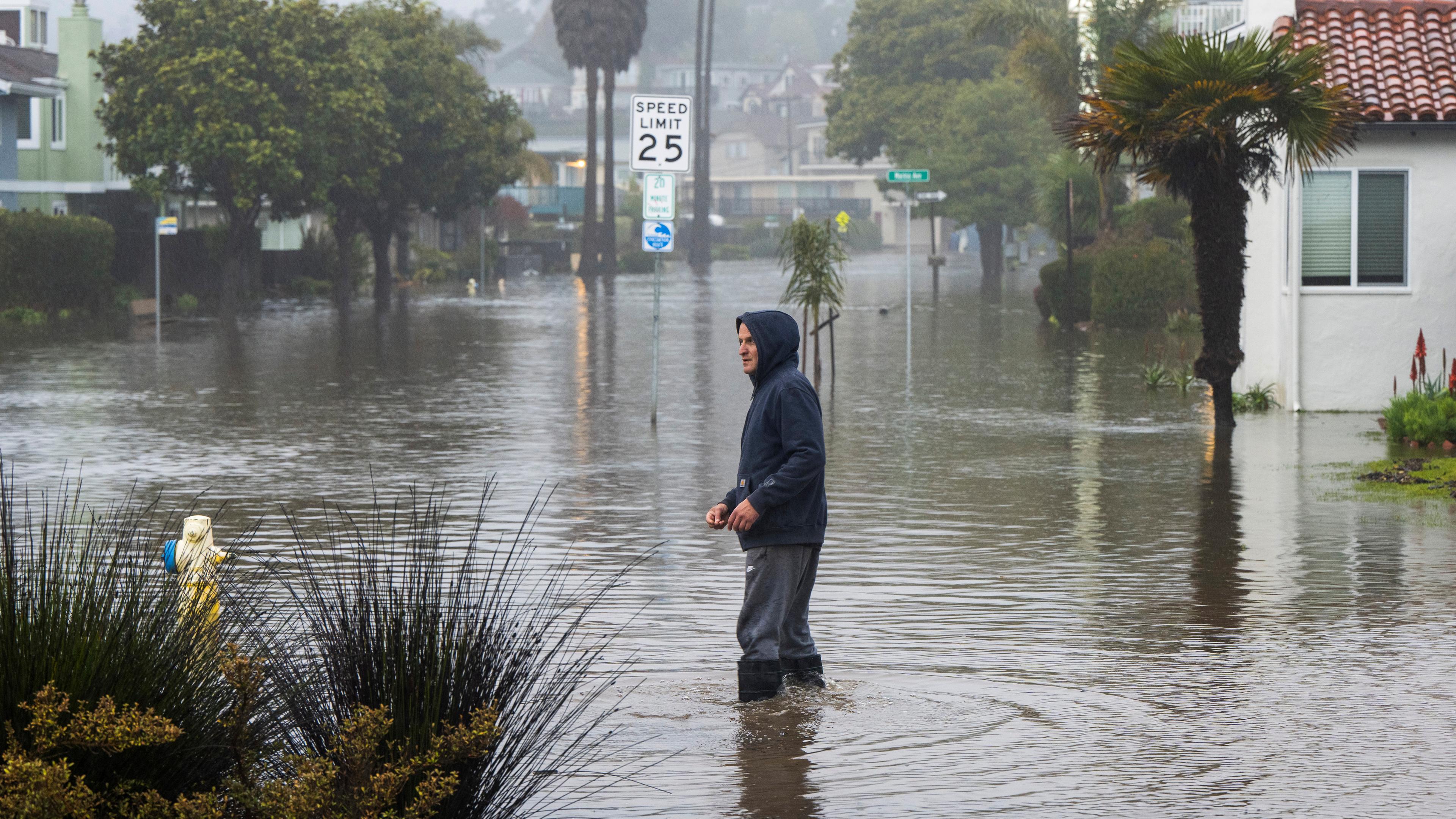Ein Mann watet durch eine überschwemmte Straße in Kalifornien