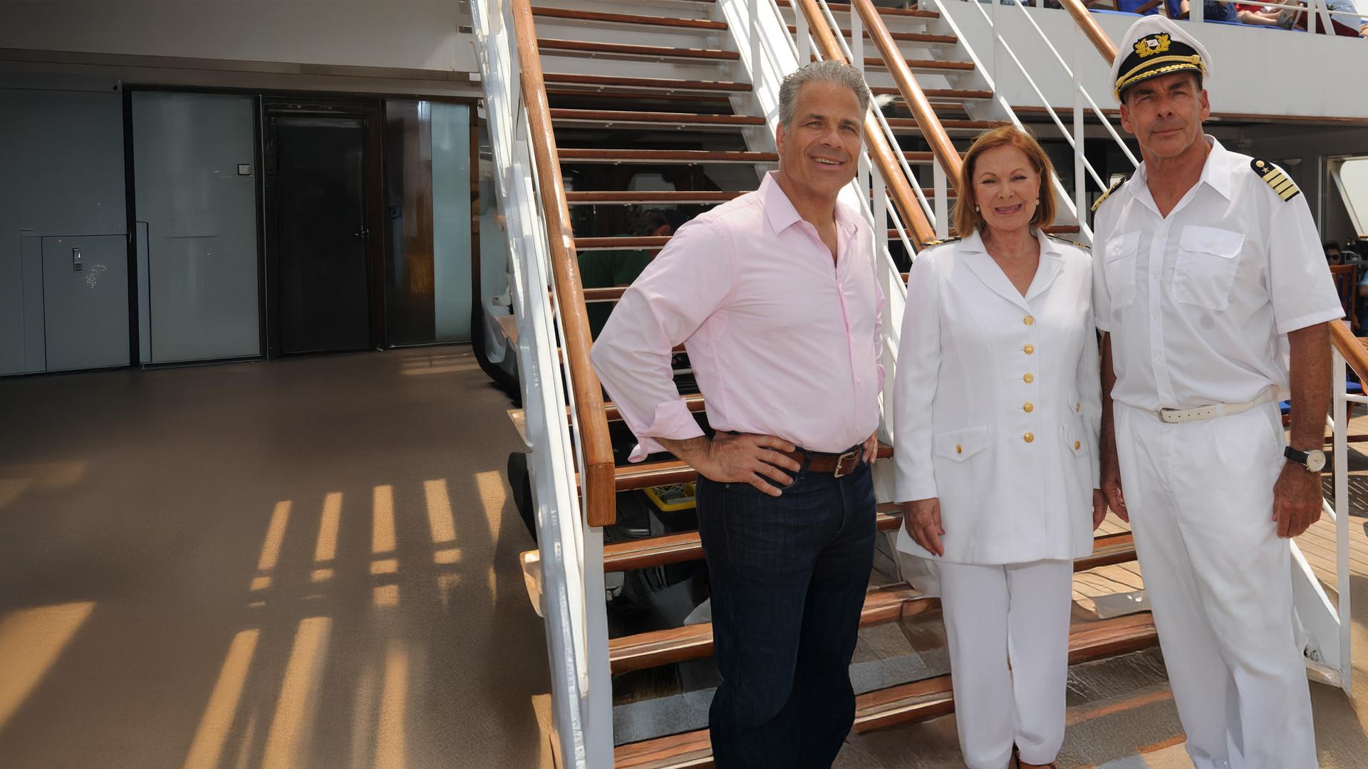 "Das Traumschiff: Kanada": Zusammen mit Peter Rand (Karsten Speck) und Beatrice (Heide Keller) steht Kapitän Burger (Sascha Hehn) an Deck des Schiffs. Sie lächeln in die Kamera.