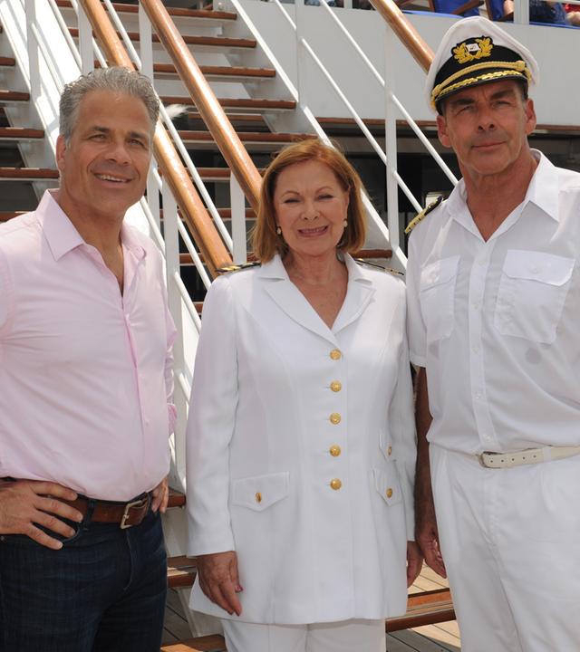 "Das Traumschiff: Kanada": Zusammen mit Peter Rand (Karsten Speck) und Beatrice (Heide Keller) steht Kapitän Burger (Sascha Hehn) an Deck des Schiffs. Sie lächeln in die Kamera.