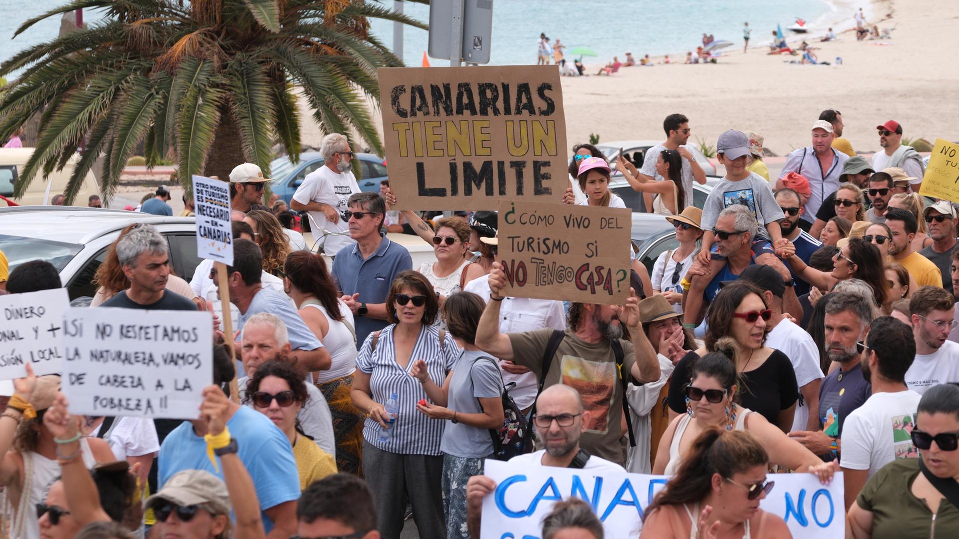 Spanien, Fuerteventura: Mehrere Personen protestieren mit Plakaten während einer Demonstration gegen das Massentourismusmodell.