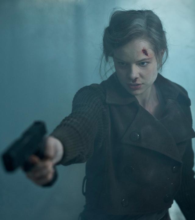 "Westwall - Kapitel II": Julia (Emma Bading) steht nach einer Explosion mit einer Pistole in der Hand im verrauchten Treppenhaus von Nicks Wohnhaus.
