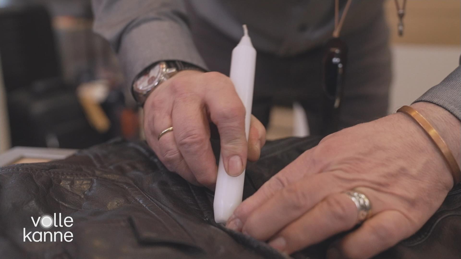 Ein Mann reibt eine Kerze am Reißverschluss einer Lederjacke.