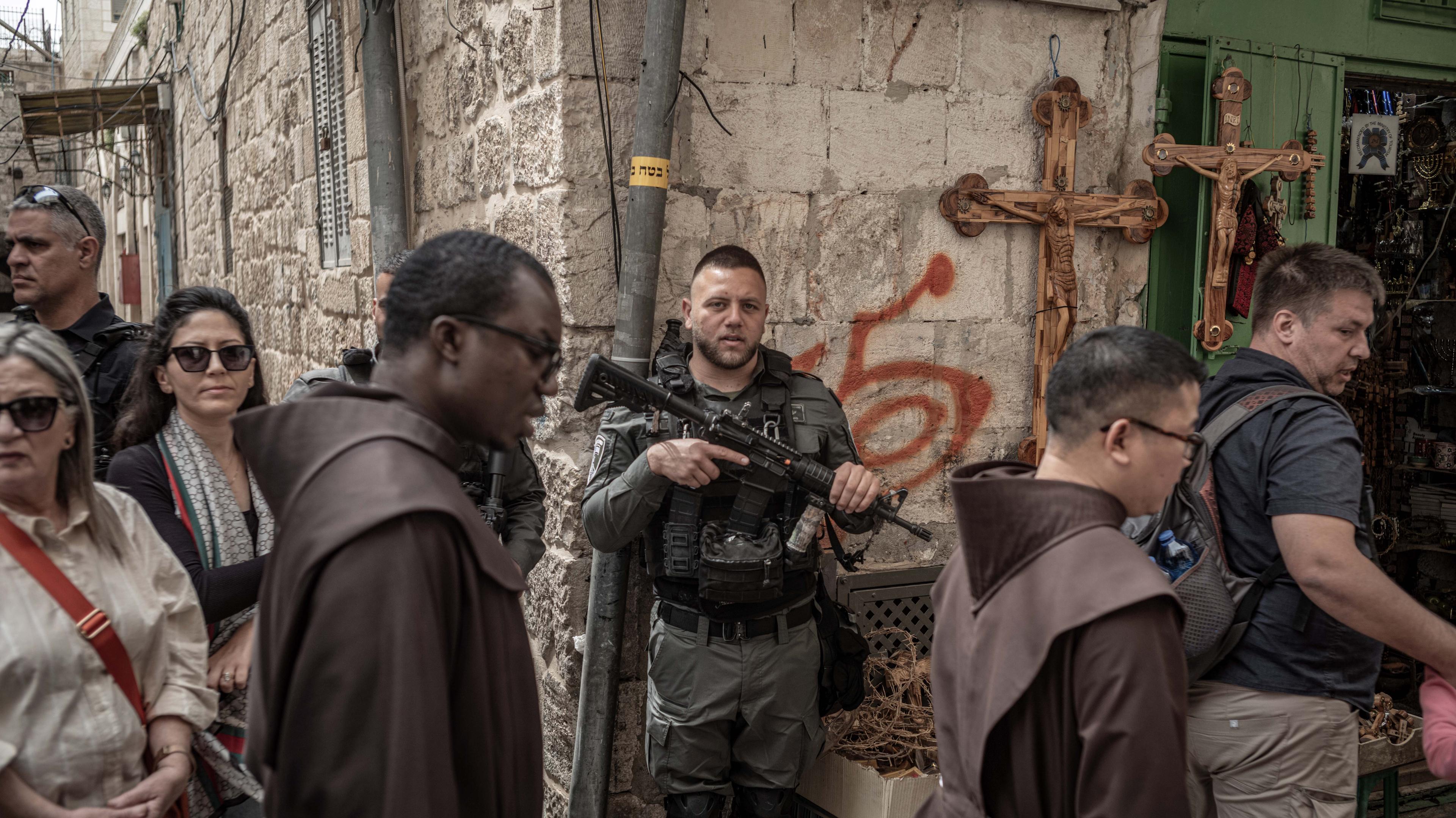 29.03.2024, Israel, Jerusalem: Ein Mitglied der israelischen Sicherheitskräfte steht, während christliche Gläubige an der Karfreitagsprozession in der Altstadt von Jerusalem teilnehmen.