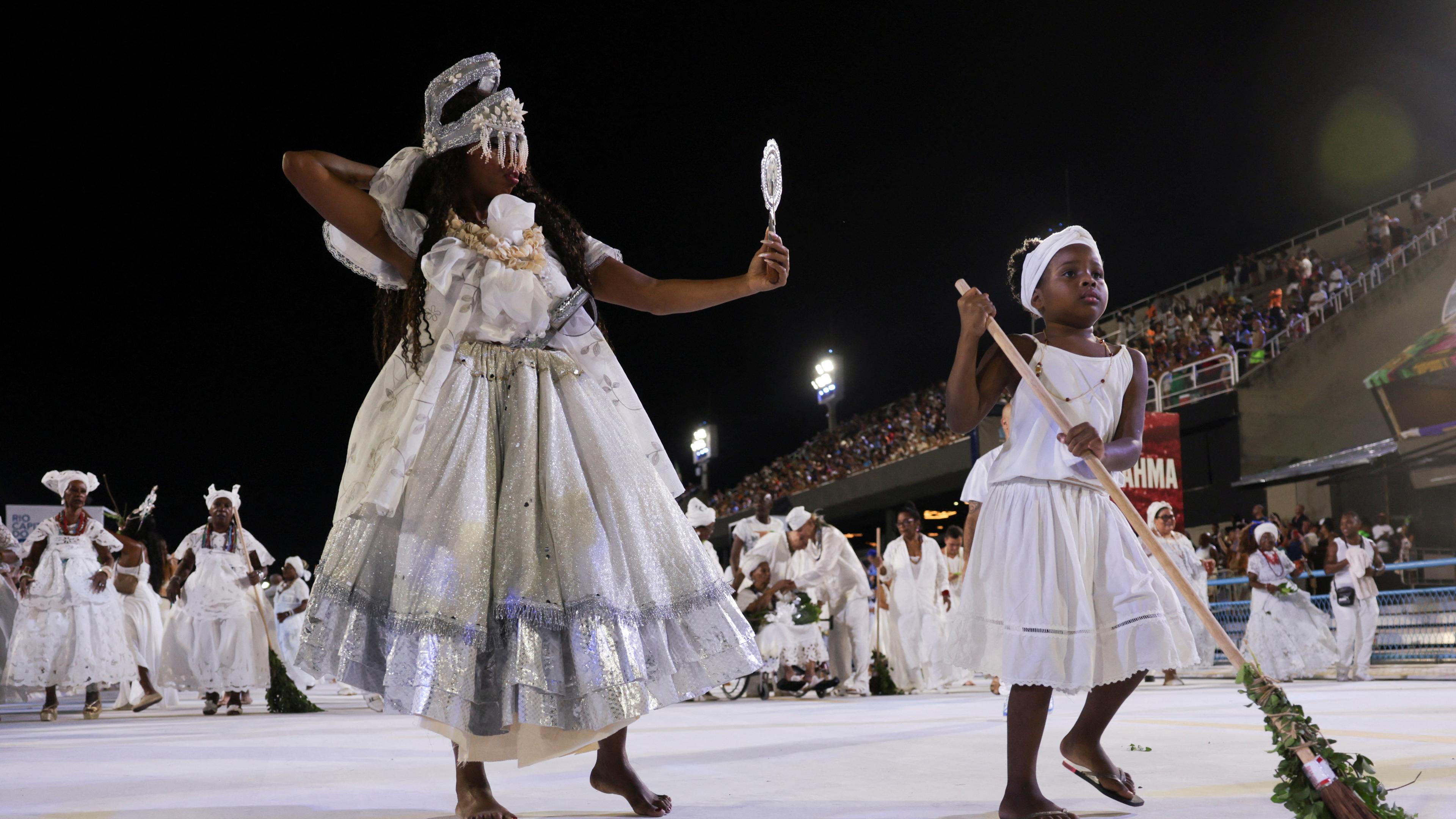 In weiß gekleidete afro-brasilianische Frauen putzen den Sambodrom vorm Karneval in Rio