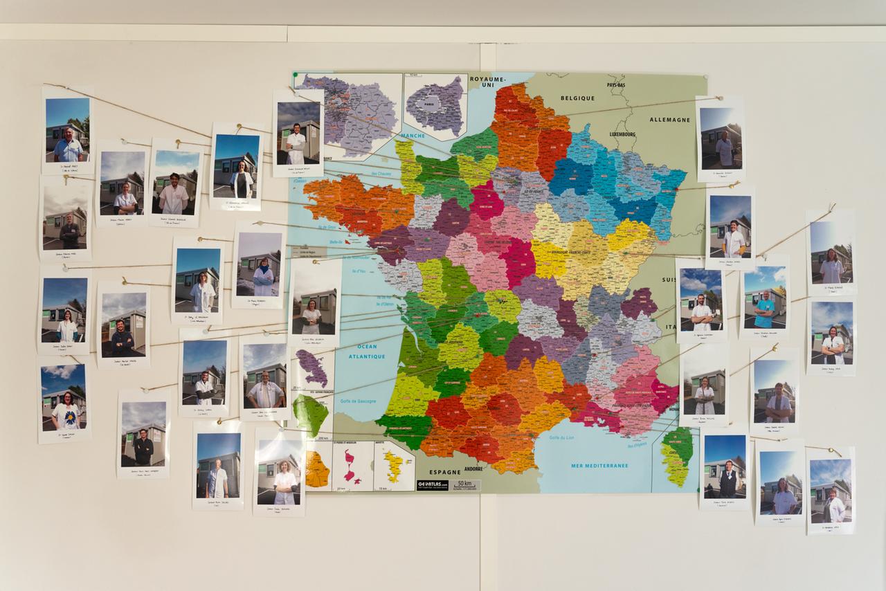 Eine Karte an einer Wand zeigt mit Fotos die vielen Ärzte und Ärztinnen, die aus ganz Frankreich gekommen sind, um in der Landarztpraxis in Ajain eine Woche zu arbeiten.