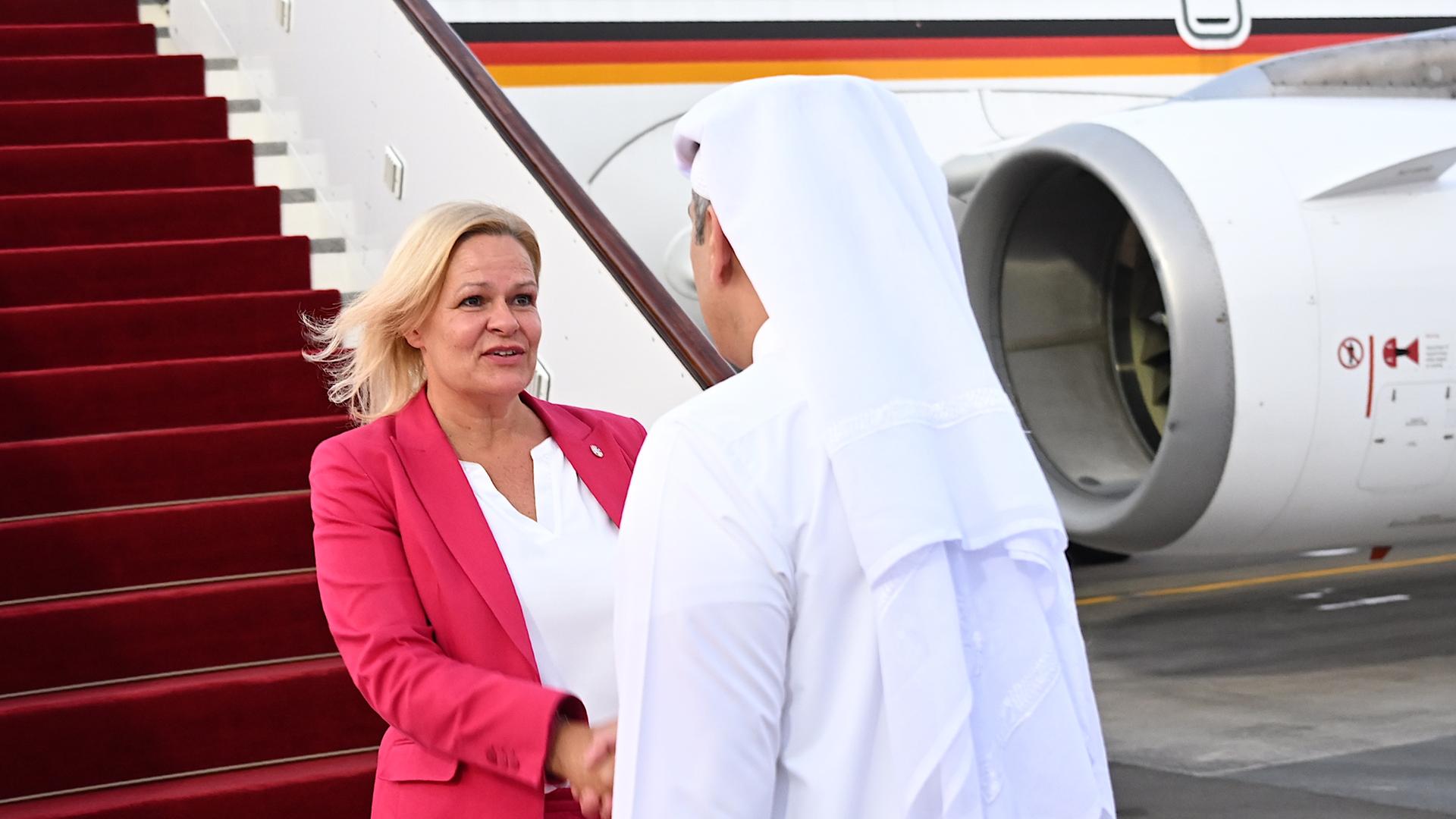 Bundesinnenministerin Nancy Faeser und der Emir von Katar schütteln sich die Hände. Im Hintergrund ein Flugzeug.