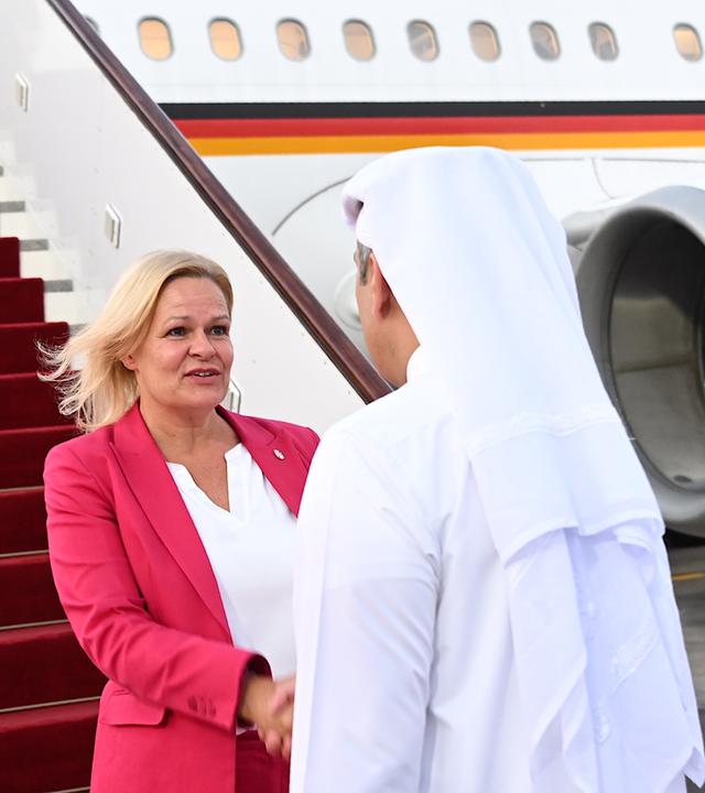 Bundesinnenministerin Nancy Faeser und der Emir von Katar schütteln sich die Hände. Im Hintergrund ein Flugzeug.