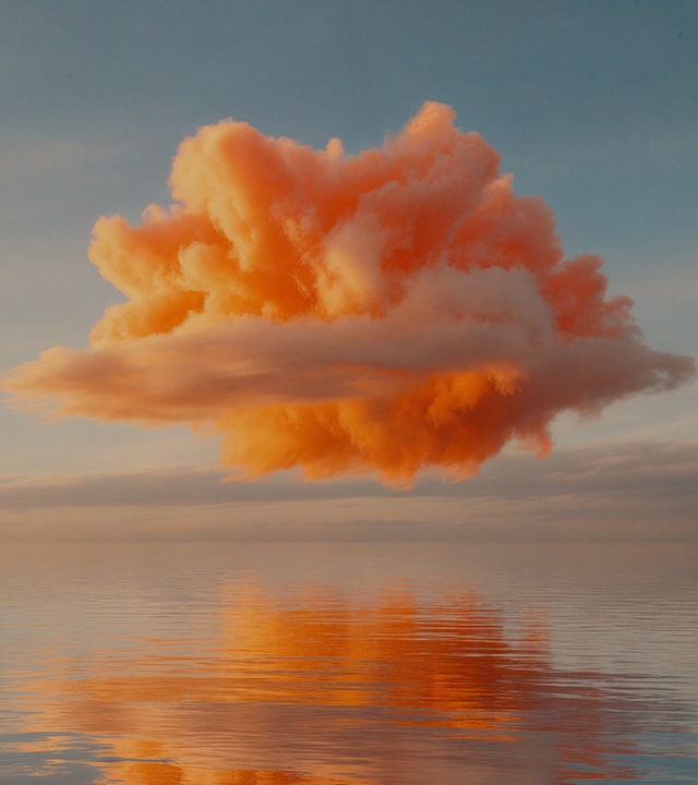 Auf dem Bild ist eine orangefarbene Wolke zu sehen. Die Wolke schwebt knapp über einerweiten und ruhigen Wasseroberfläche. In der Wasseroberfläche spiegelt sich die Wolke.