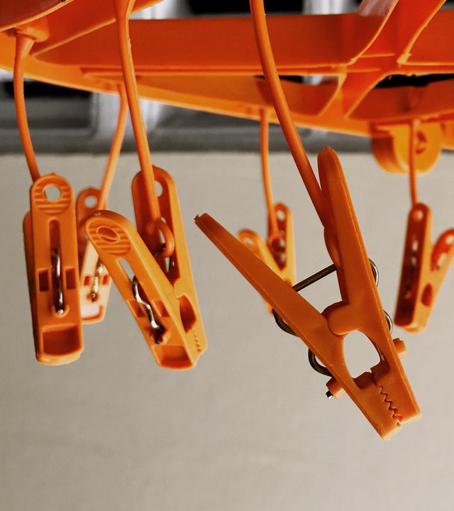 Auf dem Bild sind mehrere orangene Wäscheklammern, die von der Decke hängen, abgebildet.