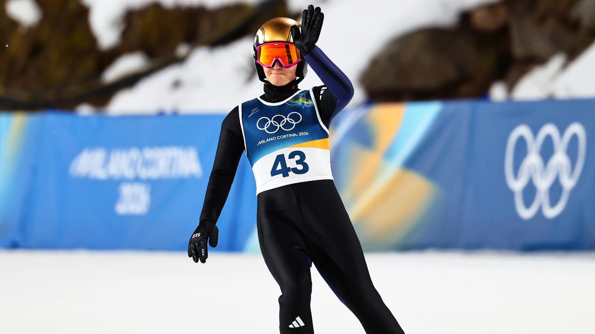 Die deutsche Skispringerin Katharina Schmid winkt nach ihrem Sprung bei den Olympischen Winterspielen 2026 in Cortina den Zuschauern zu