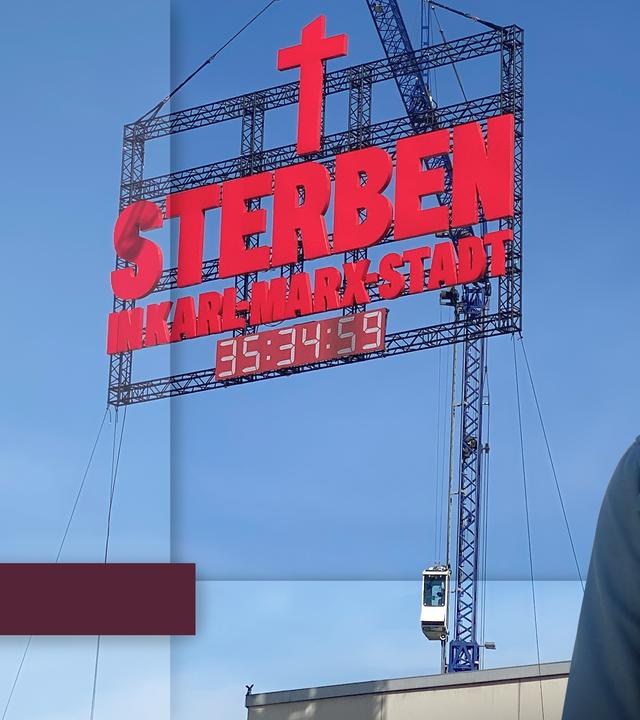 Katty Salié mit dem Schriftzug "Sterben in Karl-Marx-Stadt" im Hintergrund