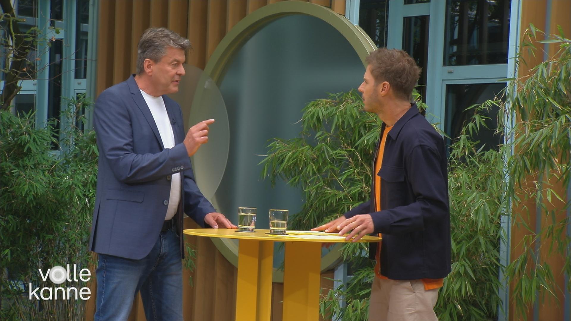 Kay P. Rodegra und Florian Weiss stehen sich an einem Stehtisch im Volle-Kanne-Atrium gegenüber.