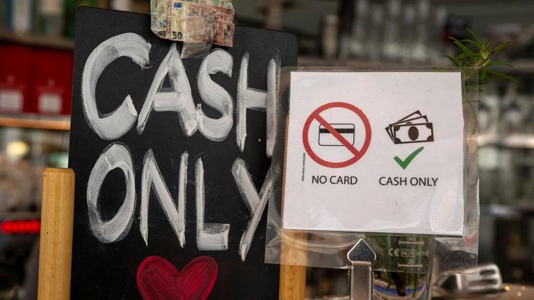 Ein Schild mit der Aufschrift «No Card - Cash Only» (Keine Karte - nur Bargeld) steht in einem Café in der Innenstadt auf einem Tresen.