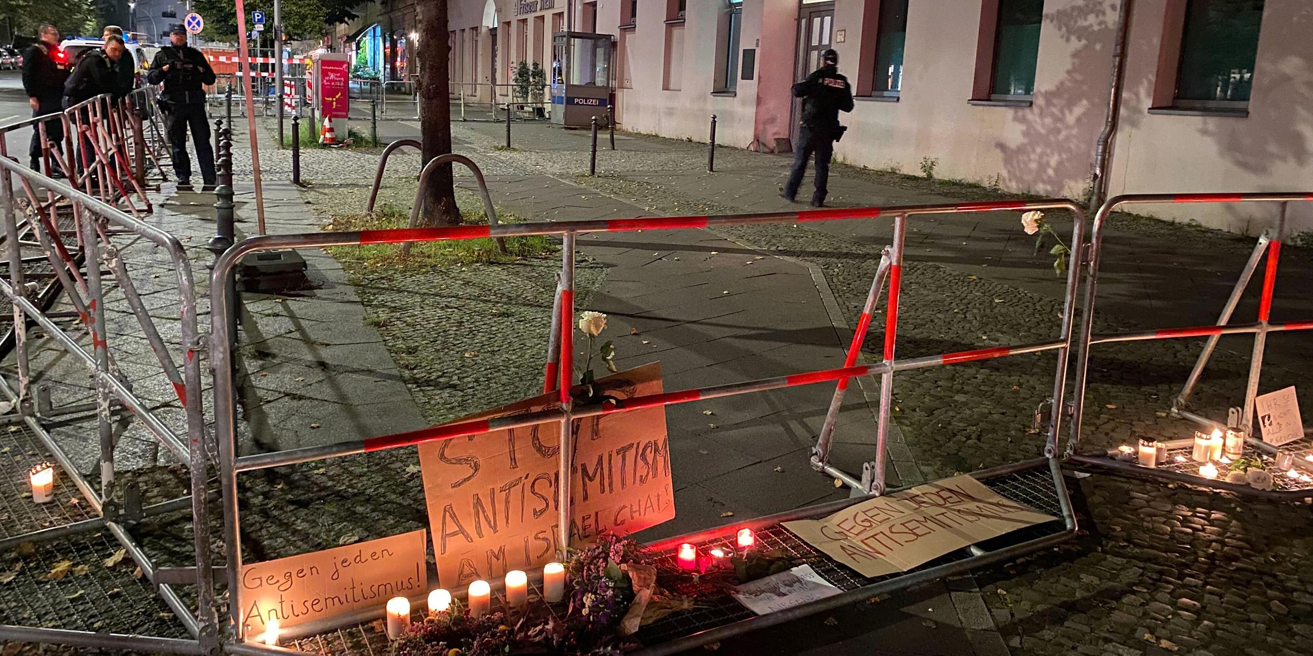 Brennende Kerzen stehen vor Schildern mit der Aufschrift "Stop Antisemitismus" an dem abgesperrten Bürgersteig vor dem jüdischen Gemeindezentrum nach dem versuchten Brandanschlag auf die Synagoge in Berlin.